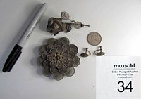 Top-down view showing two vintage silver brooches and matching pair of earrings next to a pen and coin for scale.