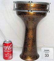 Side view of darbuka drum next to Coca Cola can for size comparison