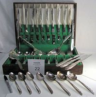 Full view of the cutlery set in wooden box with green felt lining, showing knives, forks, spoons arranged in compartments.