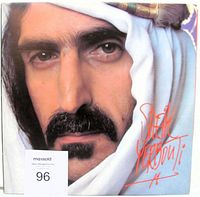 Front cover of Sheik Yerbouti double LP by Frank Zappa, showing detailed close-up of Zappa's face with white headwrap and red stylized title text.