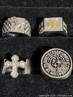 Photo of all four stainless steel men's rings showing their front designs in a black display box