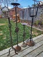 Four cast iron garden plant holders with rust and wear showing. Taking photo to show condition, style, and variety of items in the lot.