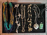 Full view of the six necklaces laid out on black velvet display.