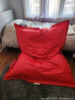 Front view of the red bean bag lounger positioned in a bedroom