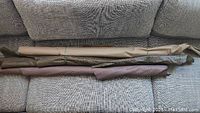 Three long leather pieces rolled or folded over a couch, showing overall size and coloration.