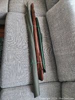 Three rolls of leather placed on a gray fabric couch, showing the relative sizes and colors (green, brown, dark green)