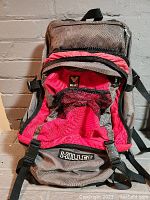 Front view of gray and red Millet 30L rucksack showing multiple pockets and Millet logo on the front bottom pocket.