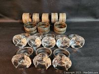 Two sets of eight napkin rings: one with metal bands having glittery stripes, another with metal rings and clear faceted crystal holders.