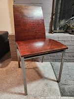 Front view of the occasional chair showing wood veneer seat and back and metal legs