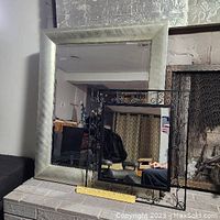 Both mirrors displayed together with a ruler for size reference; the larger one has a broad light frame, the smaller one a decorative wrought iron frame