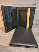 The first photo shows one leather portfolio open, displaying multiple internal compartments including slots for cards, pens, and documents alongside a ruler for size reference.