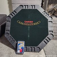 Top view of octagonal folding poker table top with green felt, black molded plastic edges with cup holders and chip slots.
