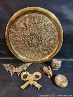 Full lot overview showing the brass charger plate floral design along with all smaller brass figurines arranged on a black backdrop.