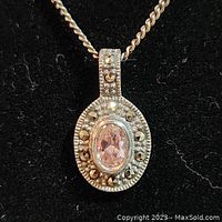 Front view of vintage silver pendant with oval pink faceted gemstone and marcasite accents on a twisted silver chain.