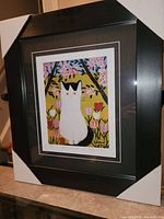 Framed fine art print of a white and black cat in floral setting by Maud Lewis with protective corner covers
