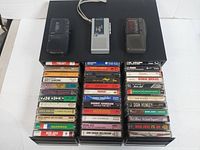Top view showing 3 cassette recorders placed above three drawers filled with 33 cassette tapes of various music artists and soundtracks.