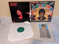 Photo of two James Brown vinyl record album covers: 'Hot Pants' (black cover with James Brown image) and 'I Got You (I Feel Good)' (colorful cover with James Brown photo). Includes visible inner sleeve and lyric insert.