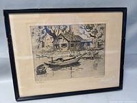 Framed etching artwork showing the full piece with visible boats, house, and water scene.