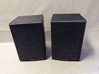 Pair of Polk Audio R150 bookshelf speakers with black fabric grilles viewed from front slightly angled.