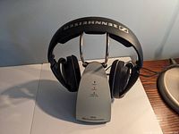 Photo showing the Sennheiser black wireless headphones on the charging base with visible Sennheiser logo on headband and ear cups.