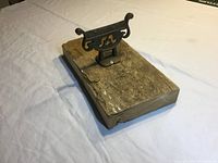 Oblique view of the antique brass boot cleaner mounted on a weathered cedar wood block showing the rust and wood wear.