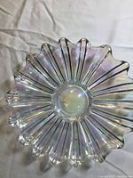 Top view of clear iridescent carnival glass plate showing floral petal pattern and ruffled edge on white background.