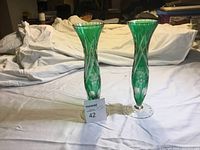 Pair of matching 11-inch tall green and clear crystal vases with floral cut pattern, flared rim, and clear base on plain white background.
