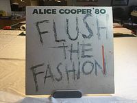 Front cover of Alice Cooper 'Flush the Fashion' 1980 LP showing graffiti-style title on white background.