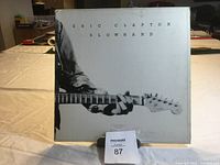 Front cover of the Eric Clapton Slowhand vinyl LP showing the black and white image of Clapton playing guitar.