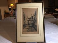 Full view of the framed etching displayed on a table showing the entire artwork, frame, and matting.