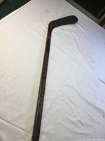 Black Sherwood composite hockey stick with red branding on shaft and blade showing model and flex details.