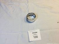 Closed view of vintage sterling silver hinged bangle bracelet on cloth background with auction tag.