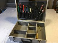 Open stainless steel lockable toolbox with padded compartments and several screwdrivers inside the tool sleeves.