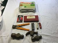 Full view of tools including hammers, multi-tool, fence wire tool, and knives arranged under the tie wrap kit box