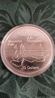Reverse side of the coin showing Olympic swimmer design, Montreal 1976 inscription, and denomination 10 Dollars.