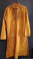 Front view of men's gold formal kurta showing embroidery on chest, collar, and cuffs with pockets and full length.