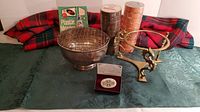 Photo showing flowering bud bowl, brass dragon stand, Celtic cross brooch in box, plastic mender kit, and multiple rolls of electrical tape on fabric background with tartan cloth.