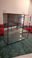 Front and slight side view of the small glass and brass display case showing compartments and brass frame.