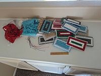 Photo showing an assortment of beaded wallets and two fabric scarves, red and blue, laid on a flat surface with a ruler for scale.