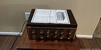 Front view of amplifier on wood table with original instruction sheet on top