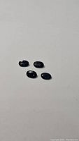 Four small oval cut blue sapphire gemstones spaced on a white surface