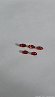 Five marquis cut fire red orange sapphire gemstones displayed under direct light showing brilliant faceted cuts and color.