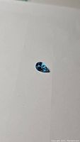 Single pear-cut natural Swiss blue topaz gemstone on a white background showing detailed facets and rich blue color.