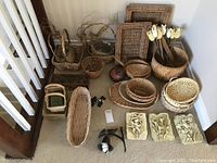 Overview of all items in the lot showing baskets, wood tulips, bell, plaques, and bird figurines arranged on the floor