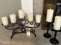 Photo showing the five-candle black metal decorative holder with five white pillar candles.