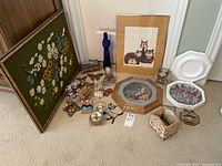 Wide view of the lot showing framed artwork, cat figurines, a blue glass bottle, and decorative plate.