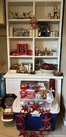 Overall view of shelves and containers with Christmas decorations including wreaths, figurines, bowls, baskets, and ribbons