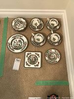 Photo of the entire tea set including cups, saucers, small plates, medium plate, and hot plate arranged on carpet