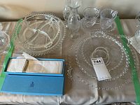 Wide view of all glassware items including serving trays, plates, vases, creamer and sugar bowl, and boxed Birks spoon on table