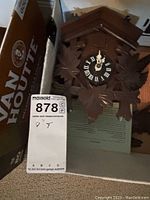 Photo showing the Black Forest cuckoo clock, carved with leaves and bird detail, Roman numeral clock face showing time 12:01.